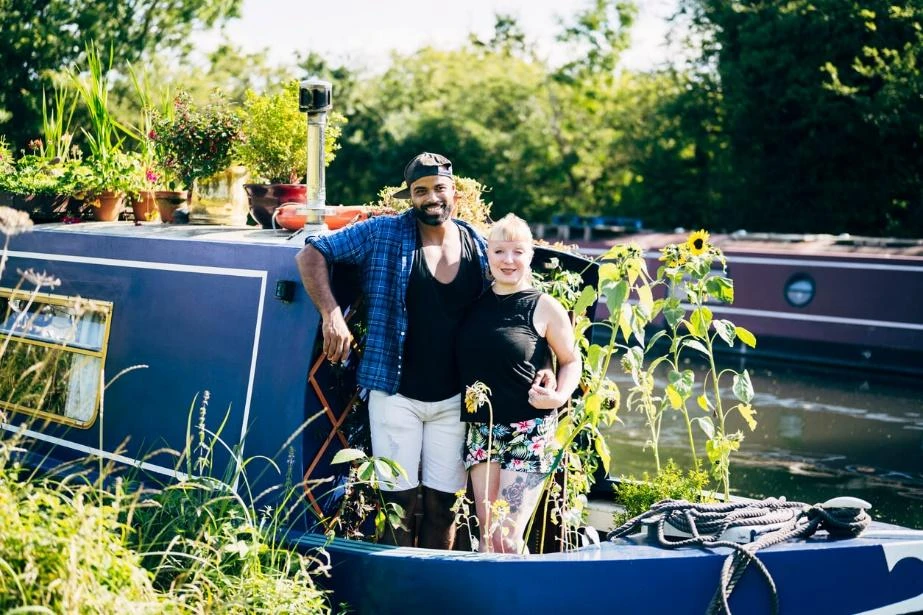 A young couple standing onboard their narrowboat