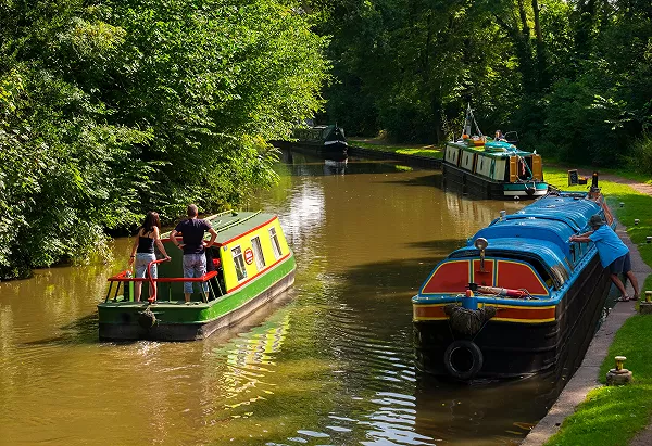 Hire boat Angela with a couple onboard cruising past other narrowboats near great haywood on the trent & mersey canal