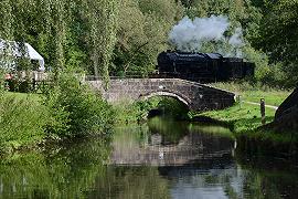 A Train passing over a stone bridge underwhich the Caldon Canal runs