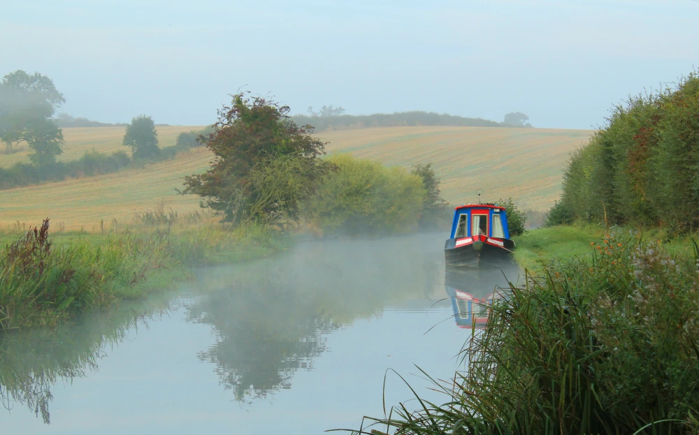 Holiday narrowboat, hired out and moored up at the side of the narrow canal