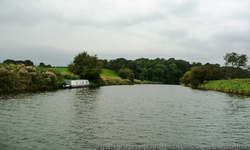 Boat moored on the river weaver, looking small by comparison with the size of the river